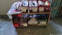 Photo shows boxed women's shoes, some marked new or used, placed on wooden shelves