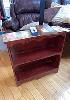 Front view of wooden bookcase showing two shelves and scalloped base edge.