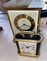 Front view of a Timex clock with brass and glass case and Roman numerals.