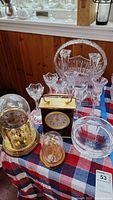 Overview of the lot with three clocks and assorted glassware on a red, white, and blue checkered cloth
