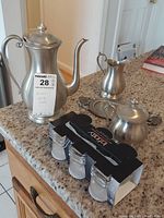 Full view of Lenox pewter tea pot, creamer, sugar bowl, metal tray and unused set of Infinity shot glasses in metal holder on kitchen counter.