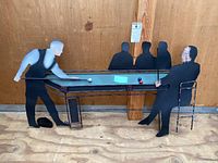 Wide angled view of the painted metal wall art showing the pool table, two main figures playing, and two seated silhouettes in background.