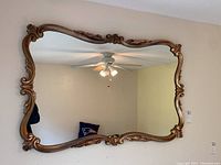 Full front view of the large rectangular mirror mounted on wall, showing the detailed carved wooden frame and reflective glass surface.