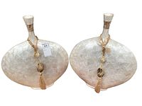 Pair of mother of pearl-like shell vases with wide bodies and narrow necks decorated with an inlaid tile pattern. Each has a hanging tassel and bead decoration from the neck.