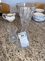 Waterford crystal pieces including a tall vase, candy dish, and small creamer on granite countertop.
