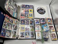 Photo showing Mets binder open with front and back pages of baseball cards visible in plastic sheets, various cards displayed in action shots and player portraits.