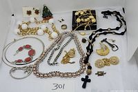 Overview of costume jewelry lot showing multiple necklaces, bracelets, earrings, pins, and a watch