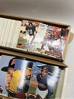 Box of NFL Pro Set football cards and visible baseball cards from Fleer showing player and team names.