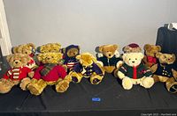 Wide shot showing all 10 Harrods collectible teddy bears sitting in a row, each with different clothing and plush colors.