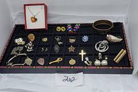Full view of the jewelry lot displayed on a black felt tray showing various jewelry pieces including chains, pins, pendants, earrings, and brooches.