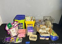 Overview of assorted lot items including buckets, bags, containers holding figurines, notepads, picture frames, and magnets.