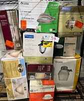 Photo shows boxed LED hanging and outdoor lighting fixtures from various brands including Lithonia Lighting, Progress Lighting, Home Decorators Collection, Hampton Bay, and Commercial Electric.