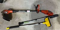 Black & Decker Grass Hog weed wacker next to two long arm brushes on the floor