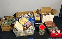 Wide view of the entire lot showing multiple boxes and bins containing assorted items including glass ornaments, mugs, and Christmas decorations.