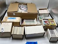 View of large quantity of sports cards stored in large and smaller boxes.