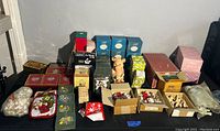 Overview of all ornaments, figurines, and holiday decoration boxes on table, mostly new in boxes