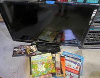 Sharp flat-screen TV with DVDs, vinyl records scattered on the floor in front of it