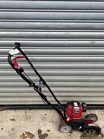 Full side view of the red Troy-Bilt lawn edger showing handle, wheels and engine housing