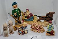 Full lot of ten vintage ceramic/porcelain figurines including Santa in sleigh, Kewpies, pig figures, huntsman, soldier, and craftsman.