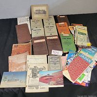 Overview of lot showing multiple vintage time books, pamphlets, brochures, and photos stacked and spread out on a surface.