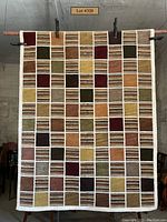 Front view of the color block wool rug with warm earth tones hung vertically showing full pattern and border.