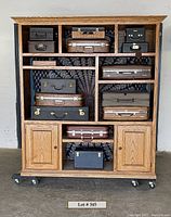 Full front view of the oak cabinet filled with vintage suitcases and storage boxes
