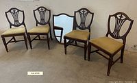 Four vintage shield back chairs with fabric seats and a vintage shield mirror with dark wood frame.