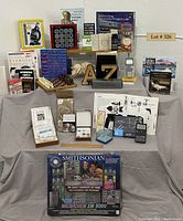 Full lot overview showing all items arranged on a table, includes boxed microchemistry set, books, chess set, model, calculators, and kits.