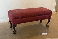 Full side and angle view of rectangular storage bench with raspberry moire brocade fabric upholstery and dark wooden claw and ball foot legs.