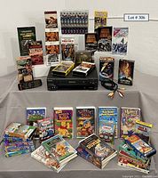 Full lot shown with Toshiba stereo VCR and assortment of mostly war/history and children’s VHS tapes.