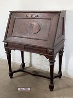 Front angle view of the Victorian Empire style secretary desk showing the hinged front panel closed, turned legs and stretcher base.