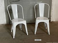 Pair of two white metal chairs with glossy finish, showing front and side angle of both chairs to depict condition and style