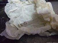 Glass radio tube wrapped in white tissue paper, showing size and metal pins at base
