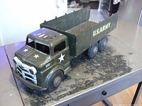 Front-side view of a 1950 Marx Lumar pressed steel army truck showing olive green body with white stars and front grill detail