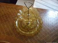 Top-down view of two-tier honey amber depression glass stand showing floral/starburst pattern and scalloped edges