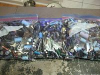 Three clear Ziploc bags filled with assorted used capacitors and electronic components visible inside, varied colors and sizes.