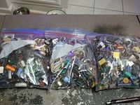 Three large zipper bags filled with assorted used electronic components, including capacitors, resistors, transistors, diodes, and other small parts.