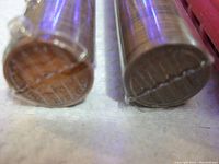 Close-up photo of two rolls of old pennies showing the ends of the rolls with visible coin edges and roll wrappers.