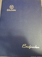 Front cover of stock album showing navy textured cover with Globe-Trotter logo and Briefmarken text