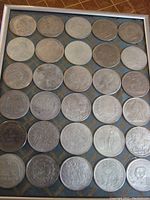 Full view of metal frame holding 6×5 grid of 30 coins on textile backing