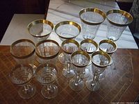 Full set of 12 stemmed glasses showing variation and gold rims.