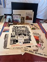 Overview of multiple signed prints, posters, book jackets laid on table