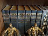 Five-volume Carl Sandburg Abraham Lincoln set and two additional history books on shelf with two metal Lincoln bookends