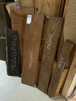 Group of five hardwood planks leaning against wall including CocoBolo, Mahogany, Benge, Benge scrap, and unidentified plank