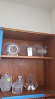 Top shelf showing three scalloped plates and one ruffled-rim bowl