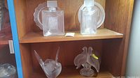 Overview of top and bottom shelf showing two bottles, two plates, planter and bird figurine