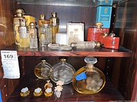 Overview of two shelves with assorted perfume bottles, boxes and bath powder jar