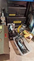Photo shows three metal toolboxes: two Stanley brand and one FAR brand, plus several electrical power tools including drills and a rotary tool.