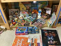 Wide shot of shelf displaying assorted Smurf figurines, mugs, puzzles, posters, trading cards and novelty toys