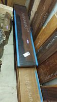 Stacked wood boards with chalk labels 'Unknown?', 'Walnut', and other species.